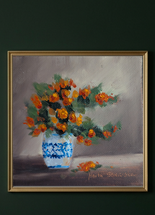 A framed still life painting featuring orange flowers in a blue and white patterned vase, set against a gray background and hung on a dark green wall.