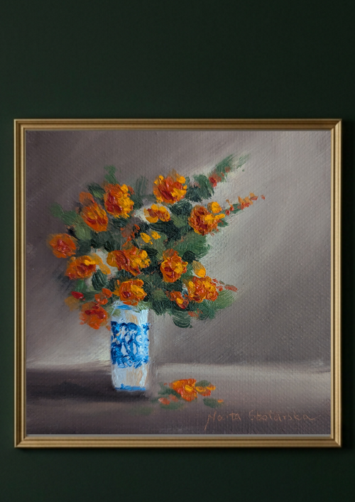 A framed still life painting featuring a bouquet of orange flowers in a blue-and-white patterned vase against a muted gray background, enclosed in a gold frame and set against a dark green wall.