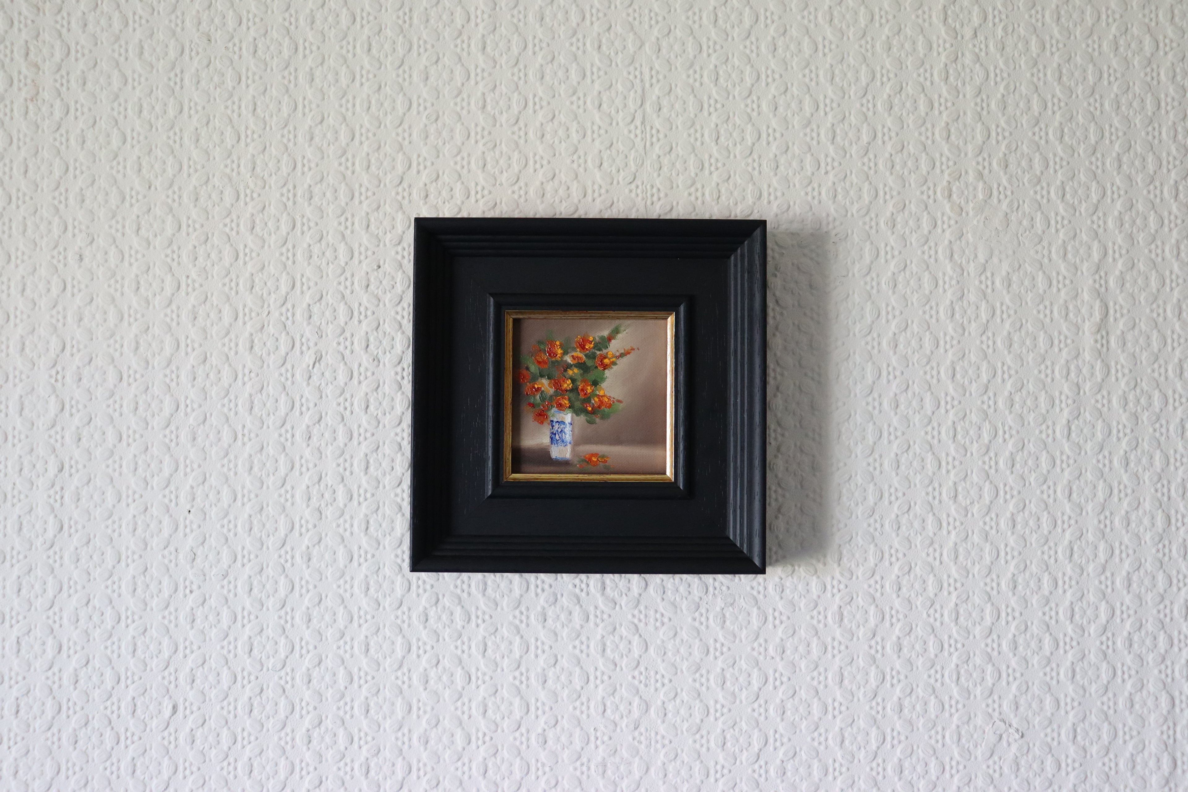 Small framed painting of a floral arrangement on a textured white wall Original oil painting of an autumnal trio of flowers or fruits, warm amber and rust tones still life