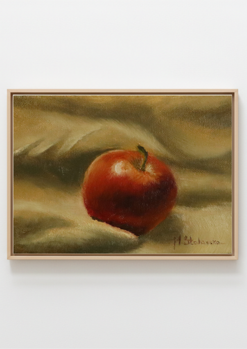 A framed still life painting of a red apple on a draped beige and brown background, shown against a plain white wall. Before the Apple Pie original oil still life  apple painting in ornate black wooden frame, approx. 18.5 x 23.5 cm, by Marta Stolarska Fine Art, ready to hang