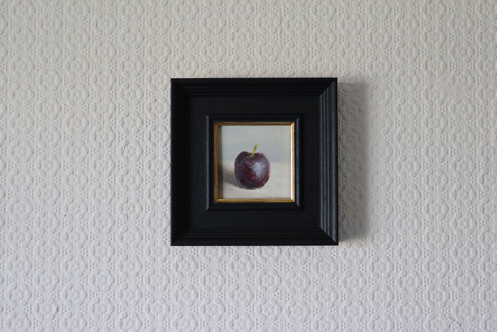 Small framed artwork of a purple plum on a textured wall. Original oil painting of blue reflections, light and colour l