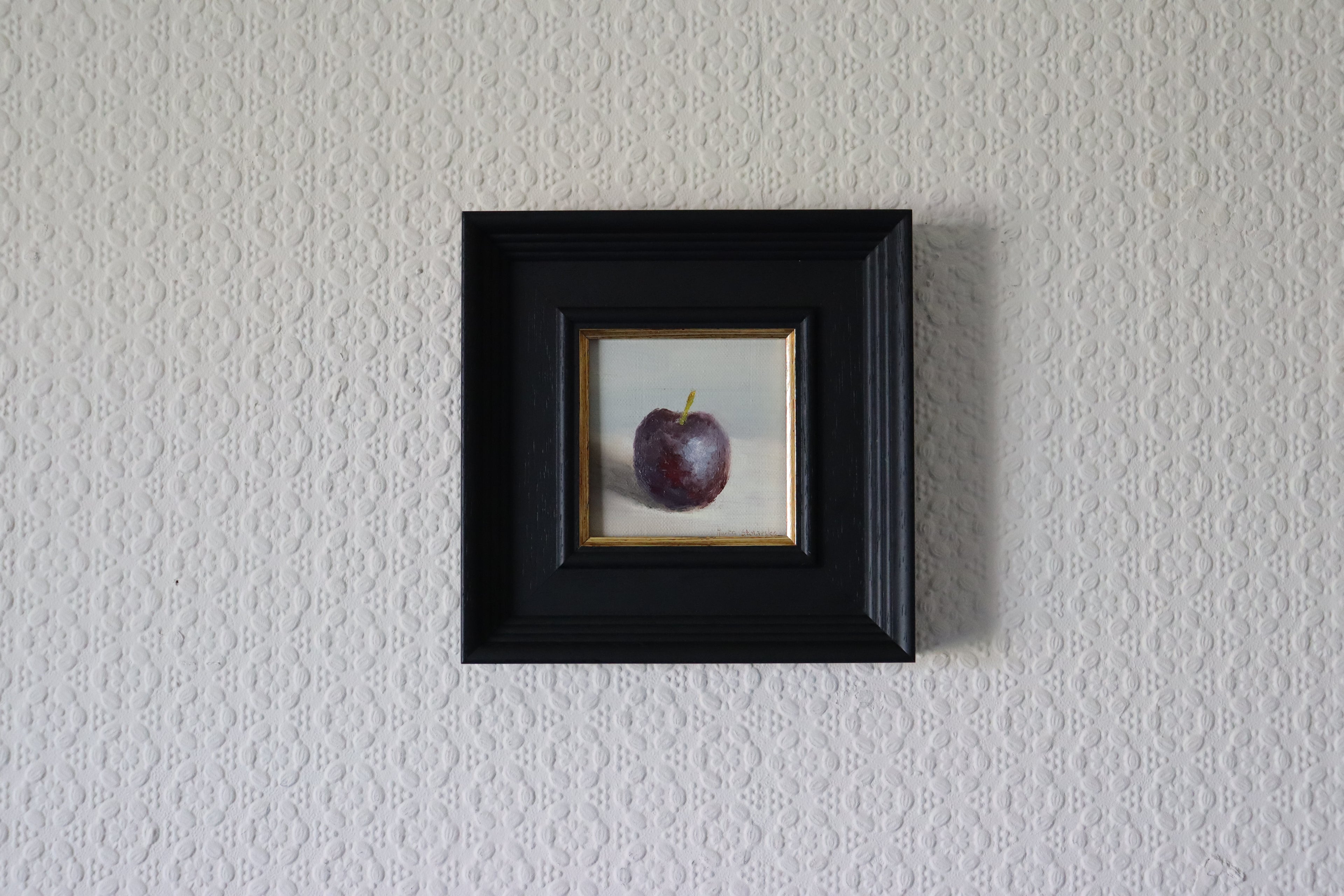 Small framed artwork of a purple plum on a textured wall. Original oil painting of blue reflections, light and colour l