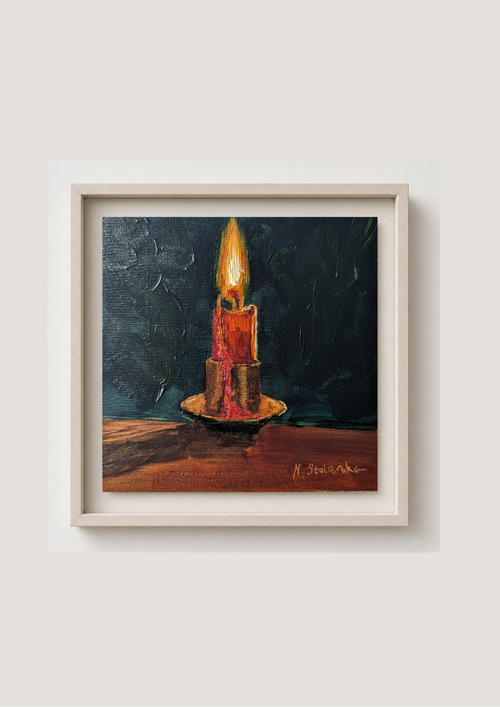 A framed oil painting of a single lit candle on a dark background, mounted on a light beige wall. The painting features a textured dark blue-green background, a glowing yellow and orange flame, a red and gold candle, and a brown surface. 