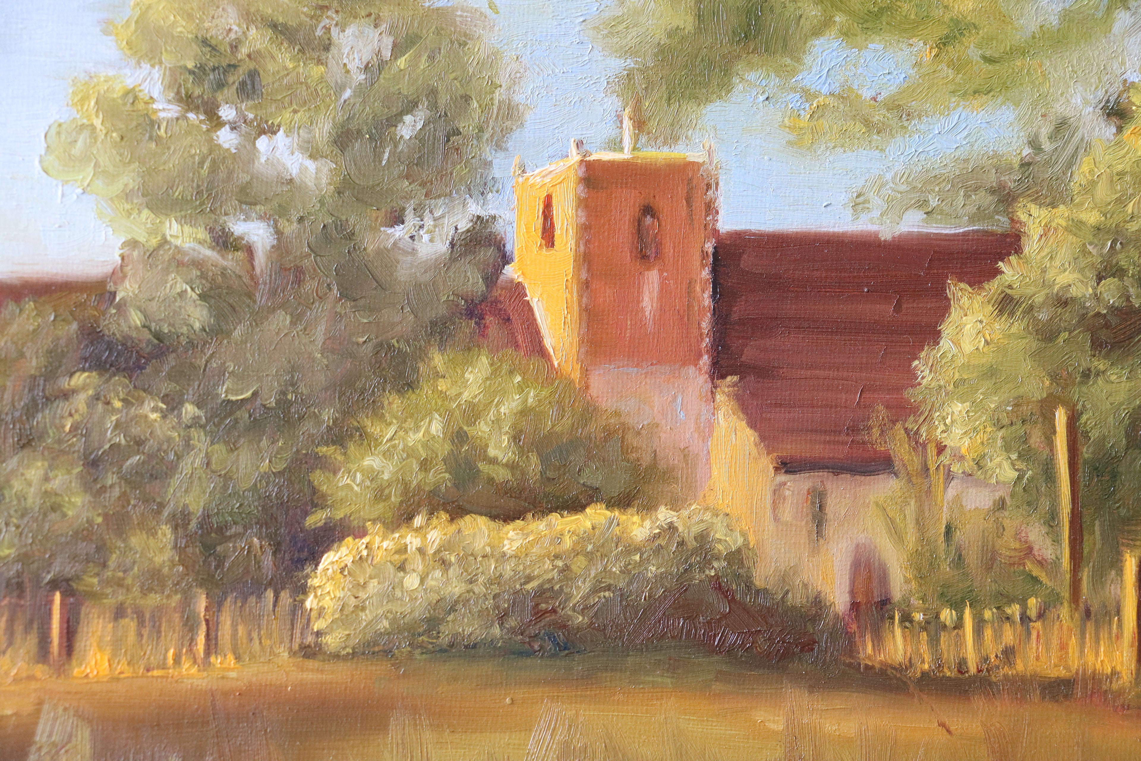 Painting of a church surrounded by trees and greenery. Original oil painting of St Michael's Church Oulton Broad Suffolk at sunset, golden light on stone