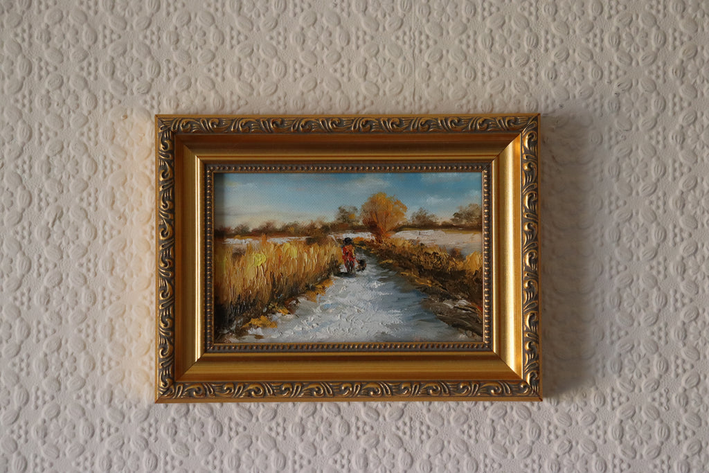 Painting of a rural scene with a person on a bike and a dog, surrounded by fields and trees by a local artist. Original oil painting of a winter walk at Suffolk marshes, snow-covered landscape with figures