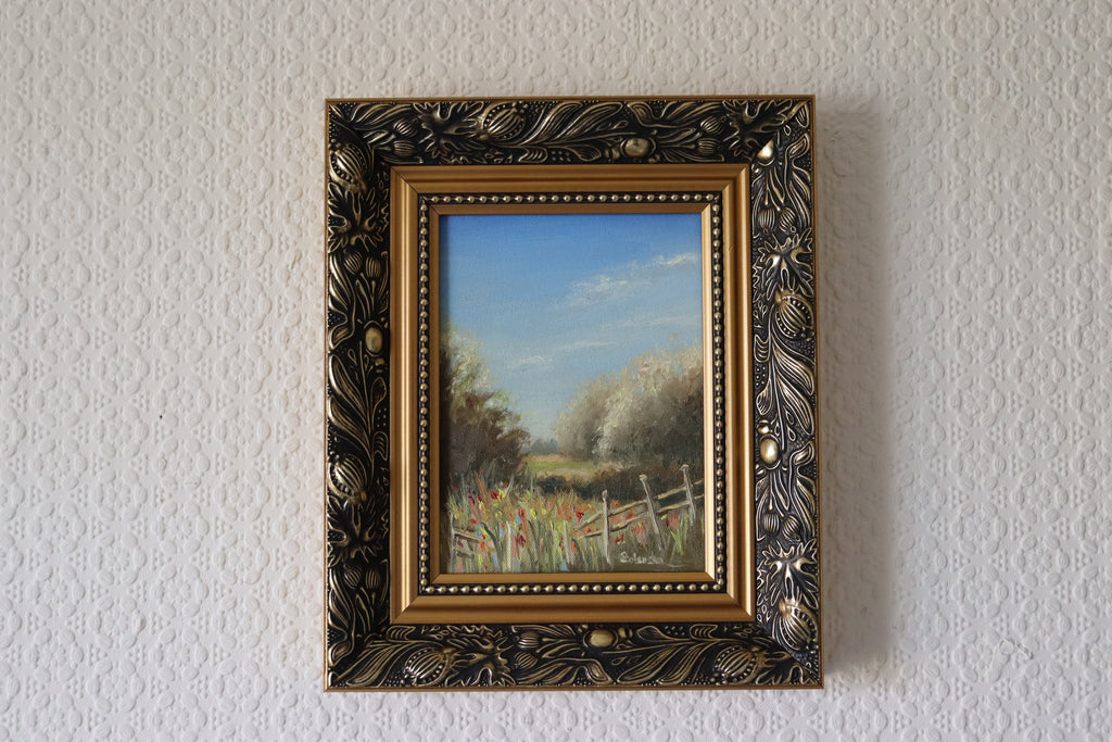 Framed painting of a landscape with trees and a fence on a textured wall. Original oil painting of a path towards the meadows at Carlton Marshes Suffolk, dilapidated fence and open fields