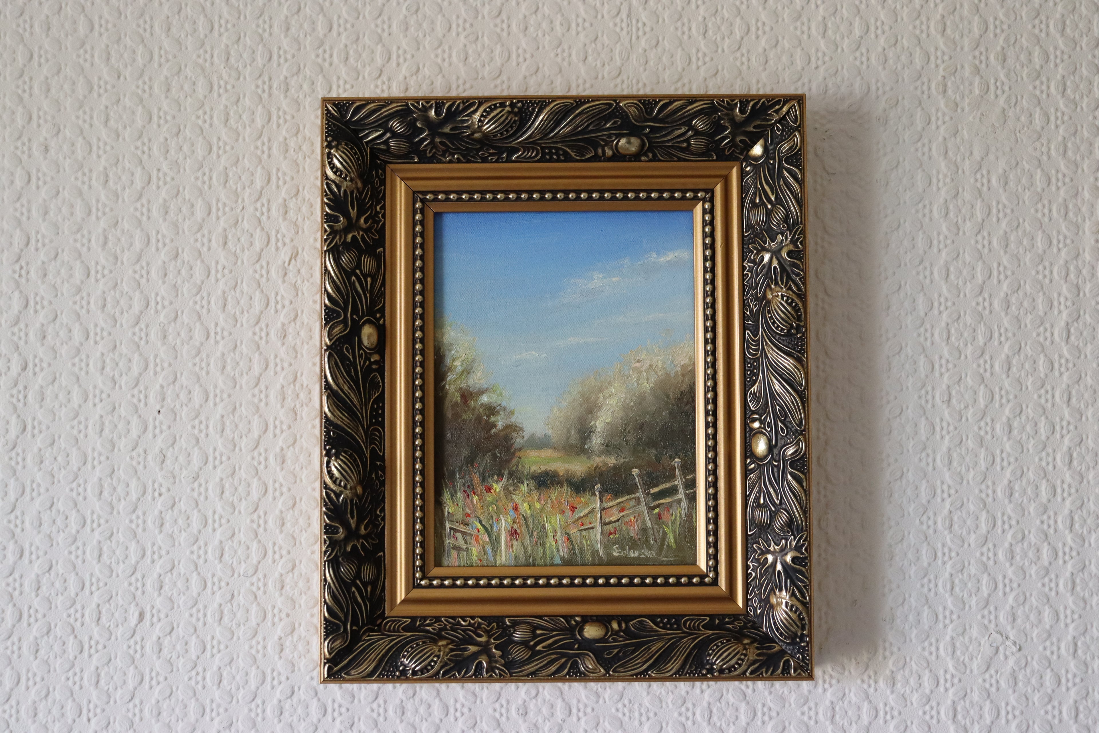 Framed painting of a landscape with trees and a fence on a textured wall. Original oil painting of a path towards the meadows at Carlton Marshes Suffolk, dilapidated fence and open fields