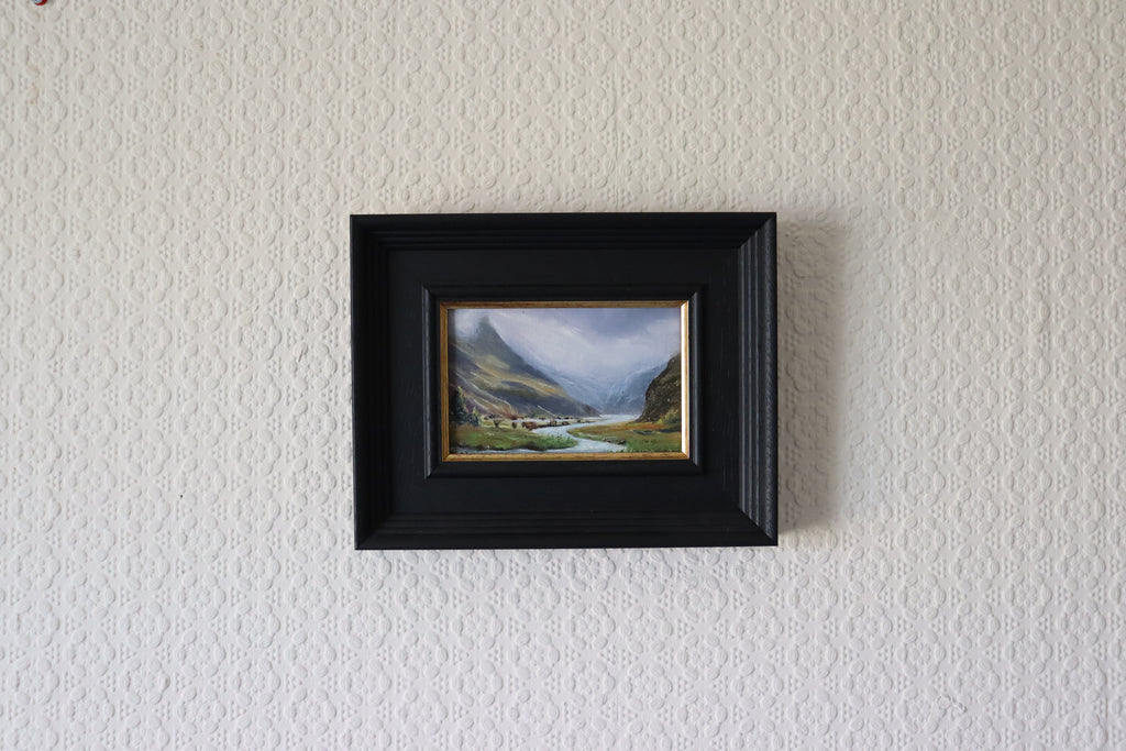 Framed landscape painting on a textured wall. Original oil painting of misty mountains landscape, atmospheric mountain scene in soft mist and cloud