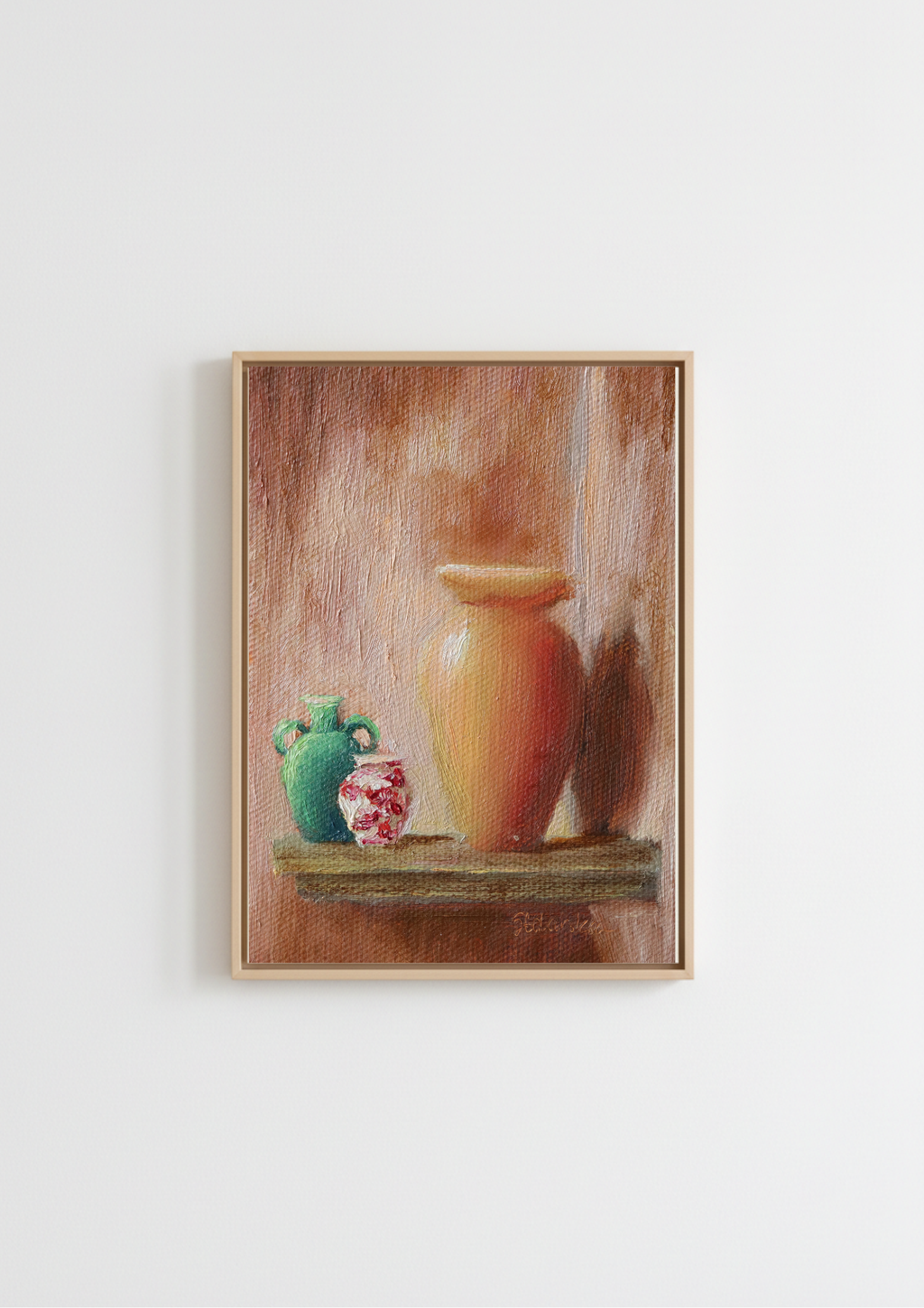 A framed still life painting featuring a large terracotta-colored vase on a shelf next to a green jug and a small red-and-white patterned pot, hung on a plain white wall.