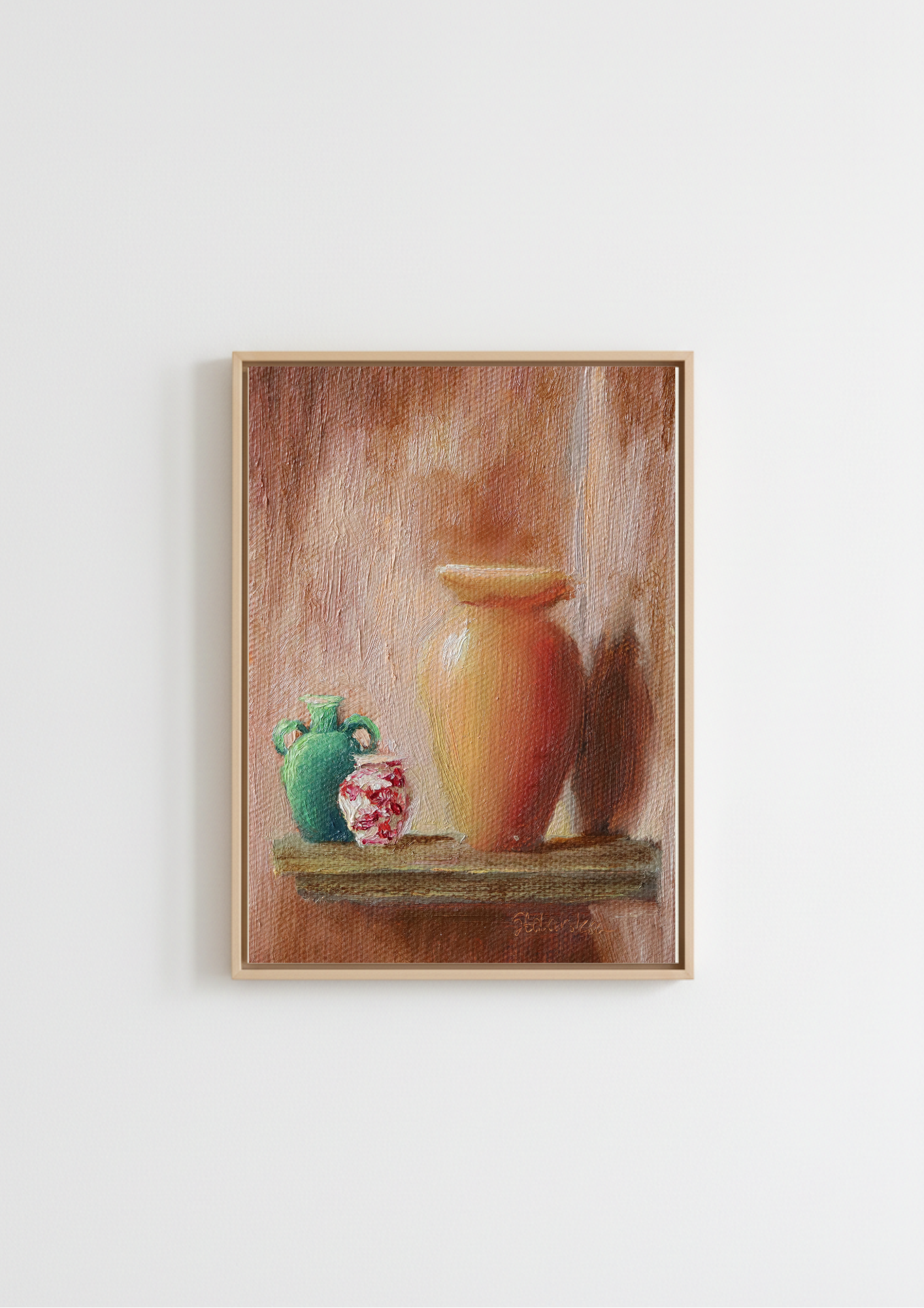 A framed still life painting featuring a large terracotta-colored vase on a shelf next to a green jug and a small red-and-white patterned pot, hung on a plain white wall.