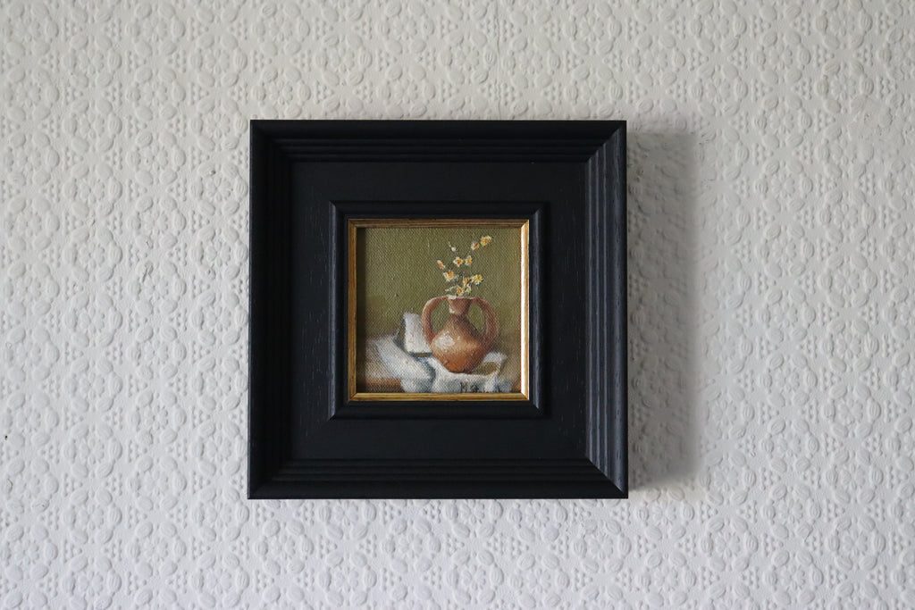 Framed Original oil painting of old terracotta, aged ceramic pot in warm earthy tones still life Small painting of a still life scene in a black frame on a textured wall.