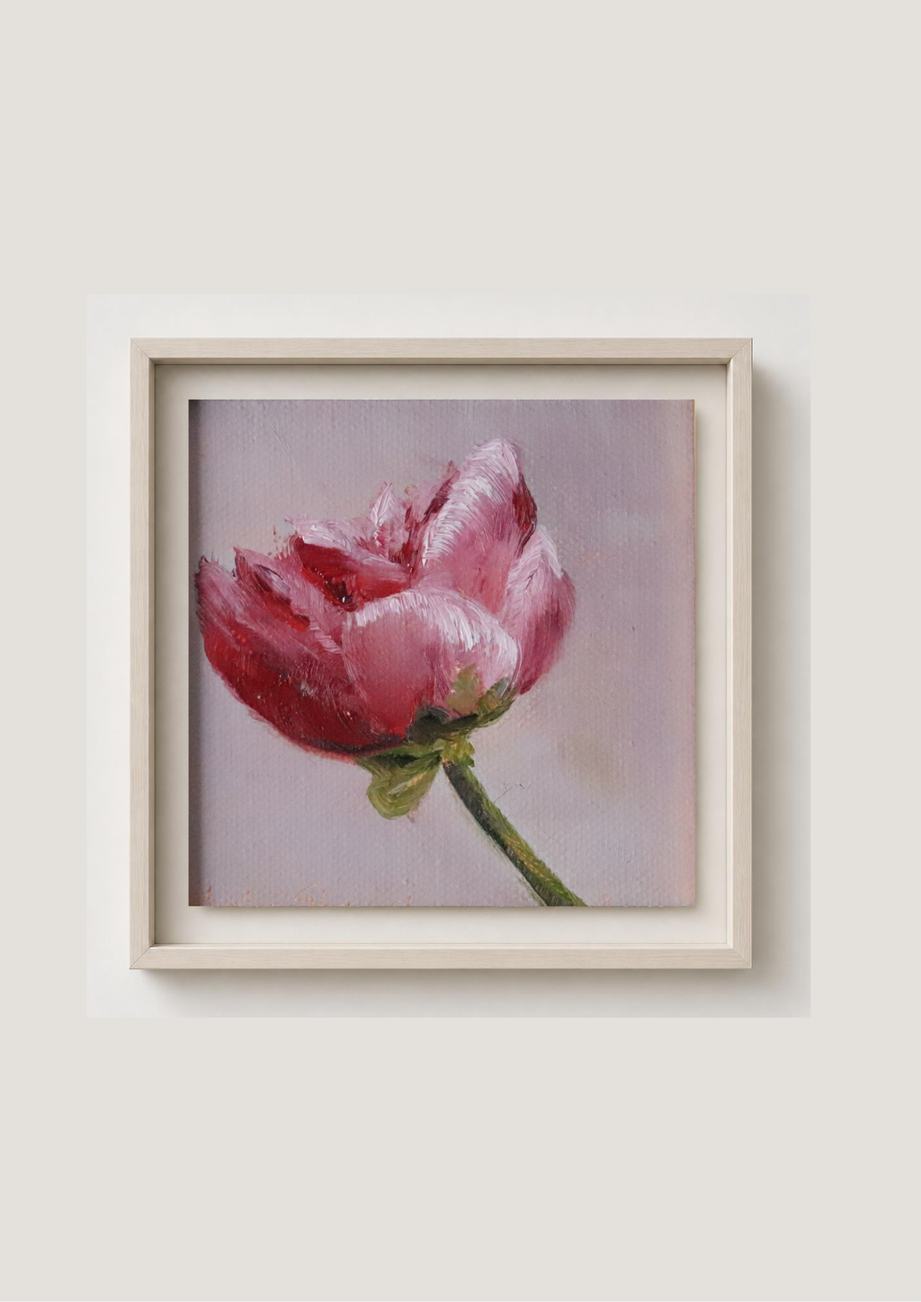 A framed painting of a pink peony on a soft lavender background, presented in a light beige frame against a neutral light gray wall.