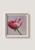 A framed painting of a pink peony on a soft lavender background, presented in a light beige frame against a neutral light gray wall.