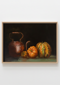 A framed still life painting featuring a copper kettle, a small orange pumpkin, and a striped green-and-orange pumpkins against a dark background, shown in a light wood frame on a white wall. Chiaroscuro sculptural techniques.