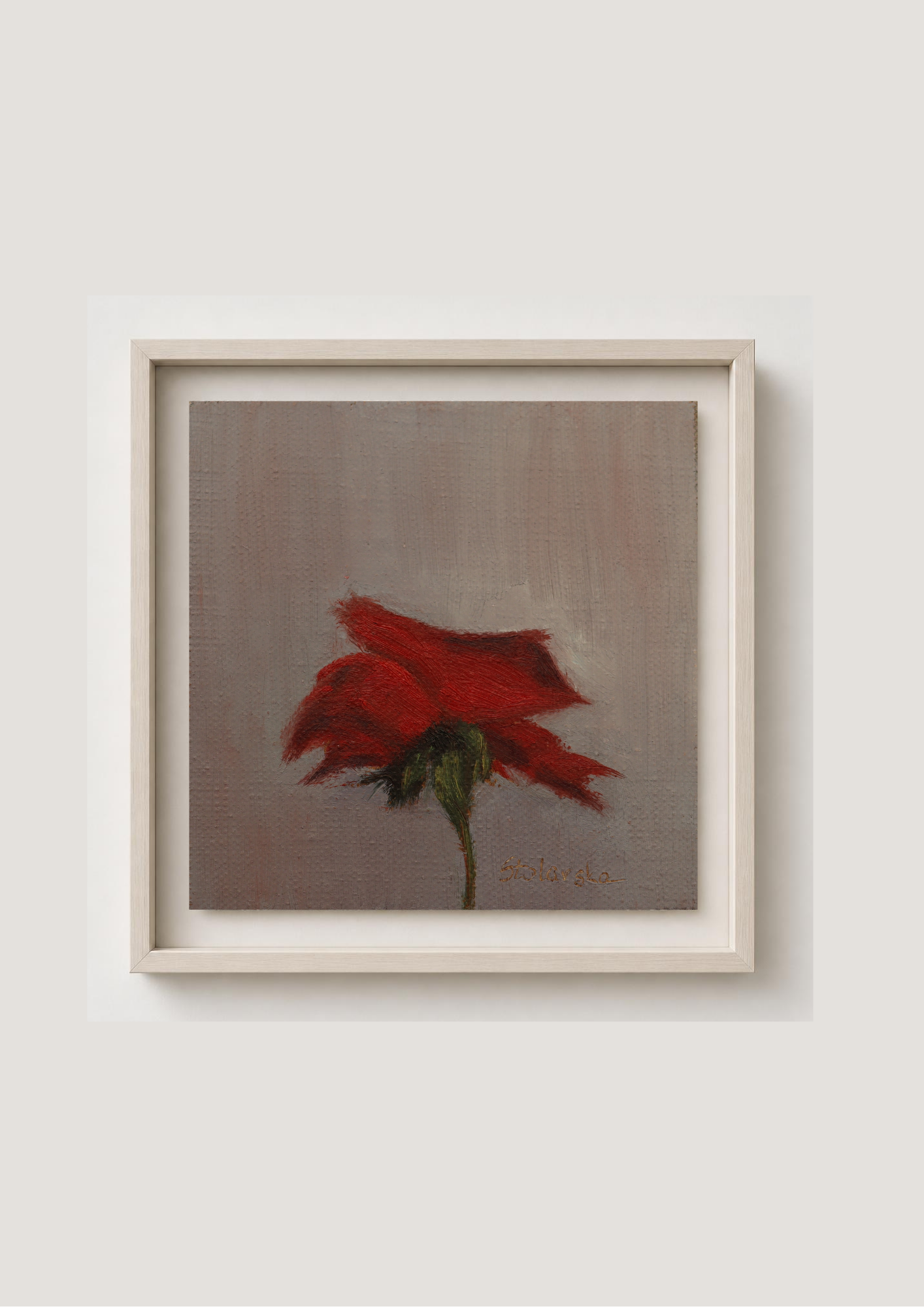 A framed painting of a single red rose with a green stem on a textured gray-brown background, enclosed in a light beige frame and mounted on a light gray wall.