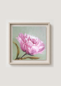 A framed painting of a pink camelia flower with green leaves on a light sage background, housed in a simple off-white wooden frame and mounted on a neutral beige wall.