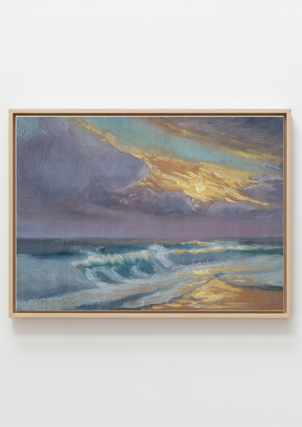 A framed landscape painting of a dramatic ocean scene with golden sunlight breaking through dark clouds, hanging on a plain white wall.