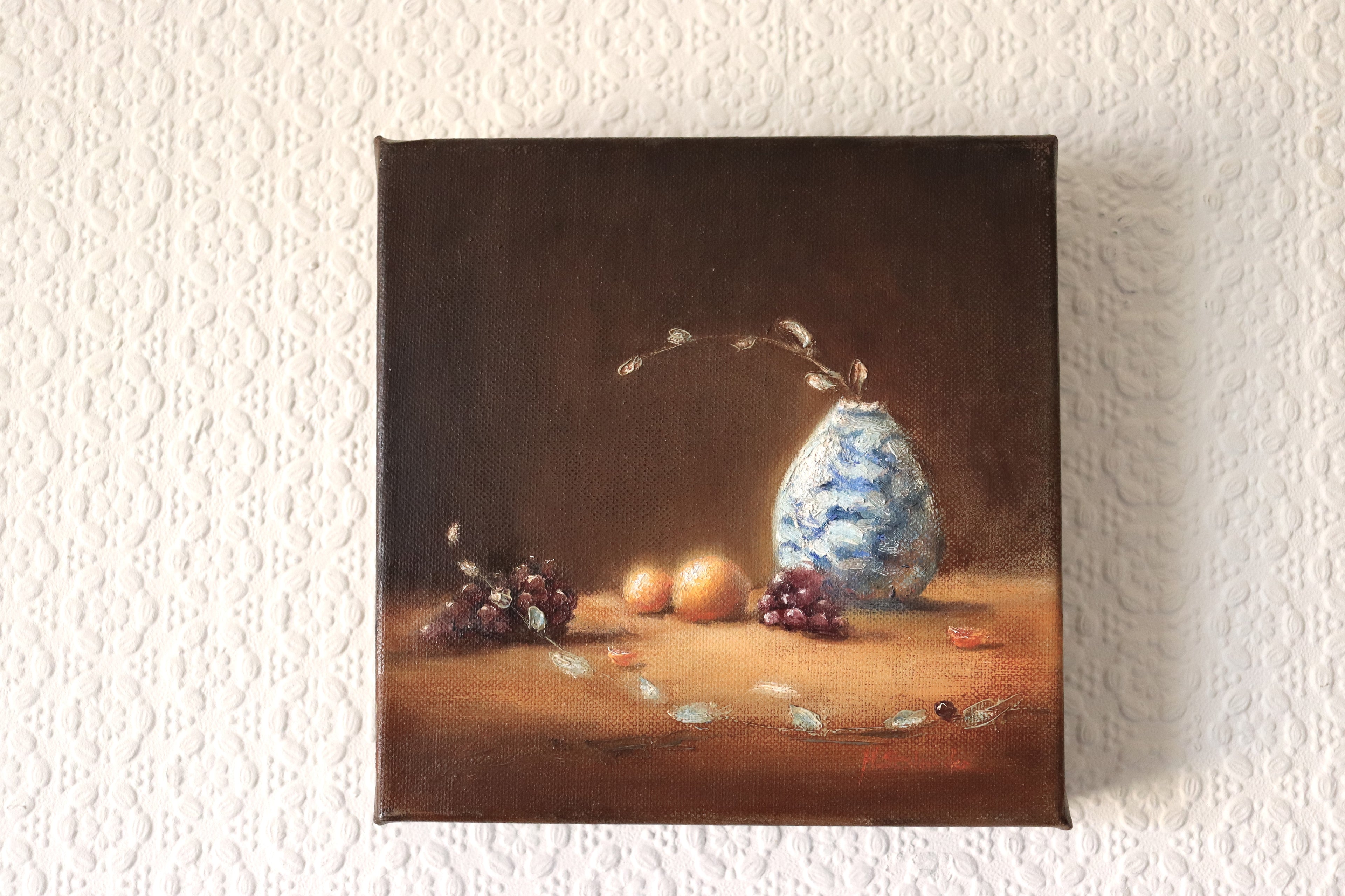 The Warmth of the Autumnal Glow original oil painting hung on a wall - autumnal still life with oranges, grapes and white blue vase, deep edge canvas 20x20cm by Marta Stolarska, ready to hang