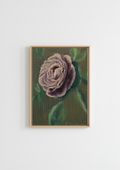 A framed vertical painting of a textured purple rose with green leaves, set in a light wood frame and hanging on a plain white wall. The Cottage Rose - original oil painting by Marta Stolarska, a full-petalled purple-mauve ranunculus rose against a sage green background, painted on handmade linen board, 10 x 15 cm