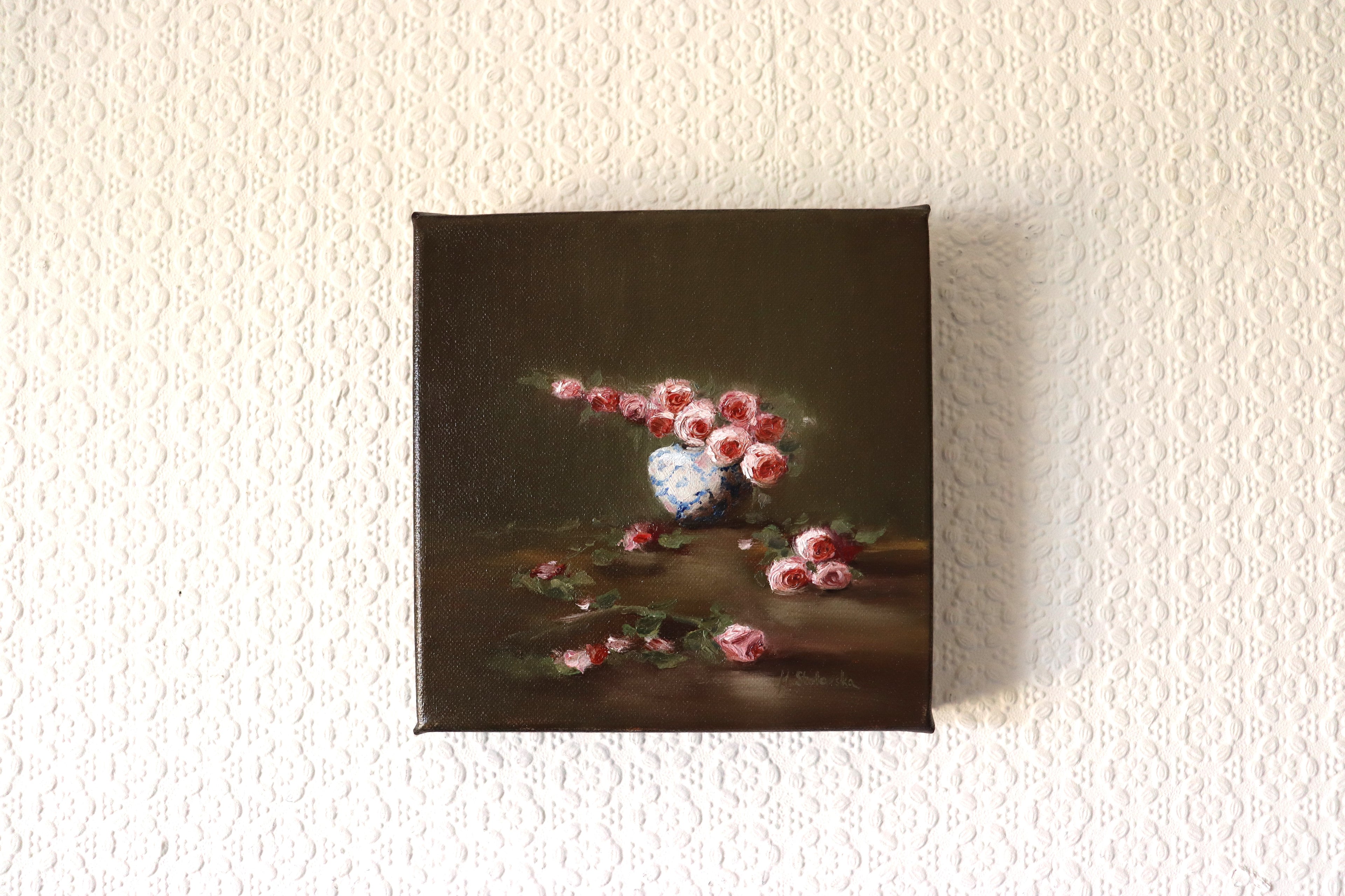 Where the Light Falls original oil painting hung on a wall - roses in white and blue vase with fallen petals, deep edge canvas 20x20cm by Marta Stolarska Fine Art, ready to hang