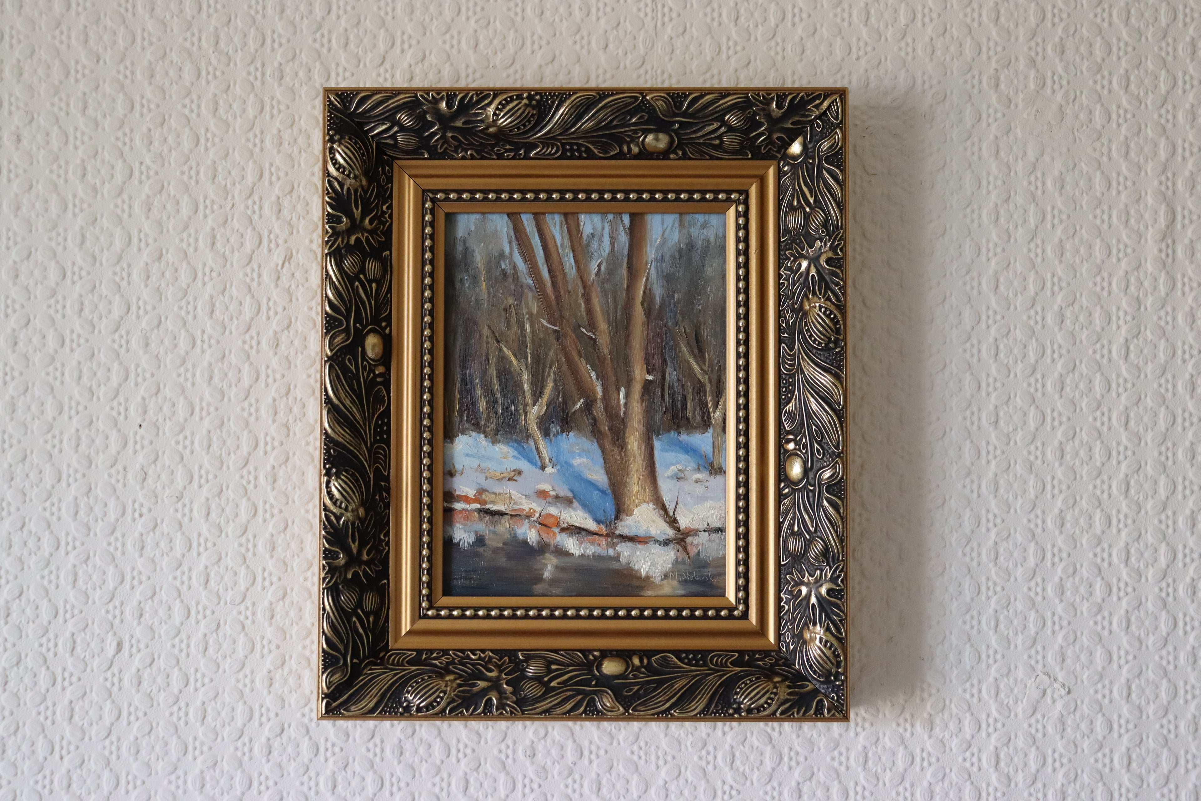 Framed painting of a winter landscape on a white wall