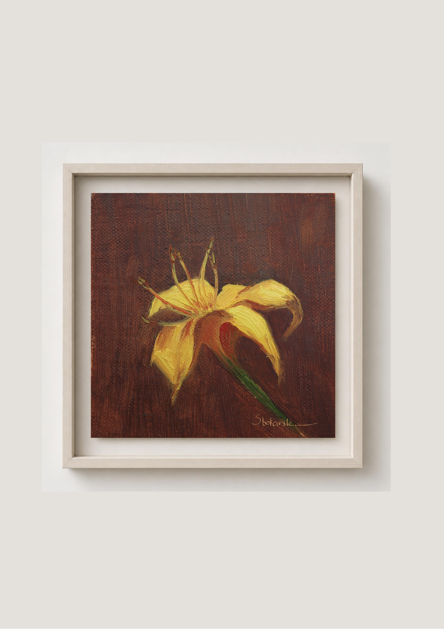 A framed painting of a yellow lily on a dark brown textured background, presented in a light-colored wooden frame against a neutral light gray wall.