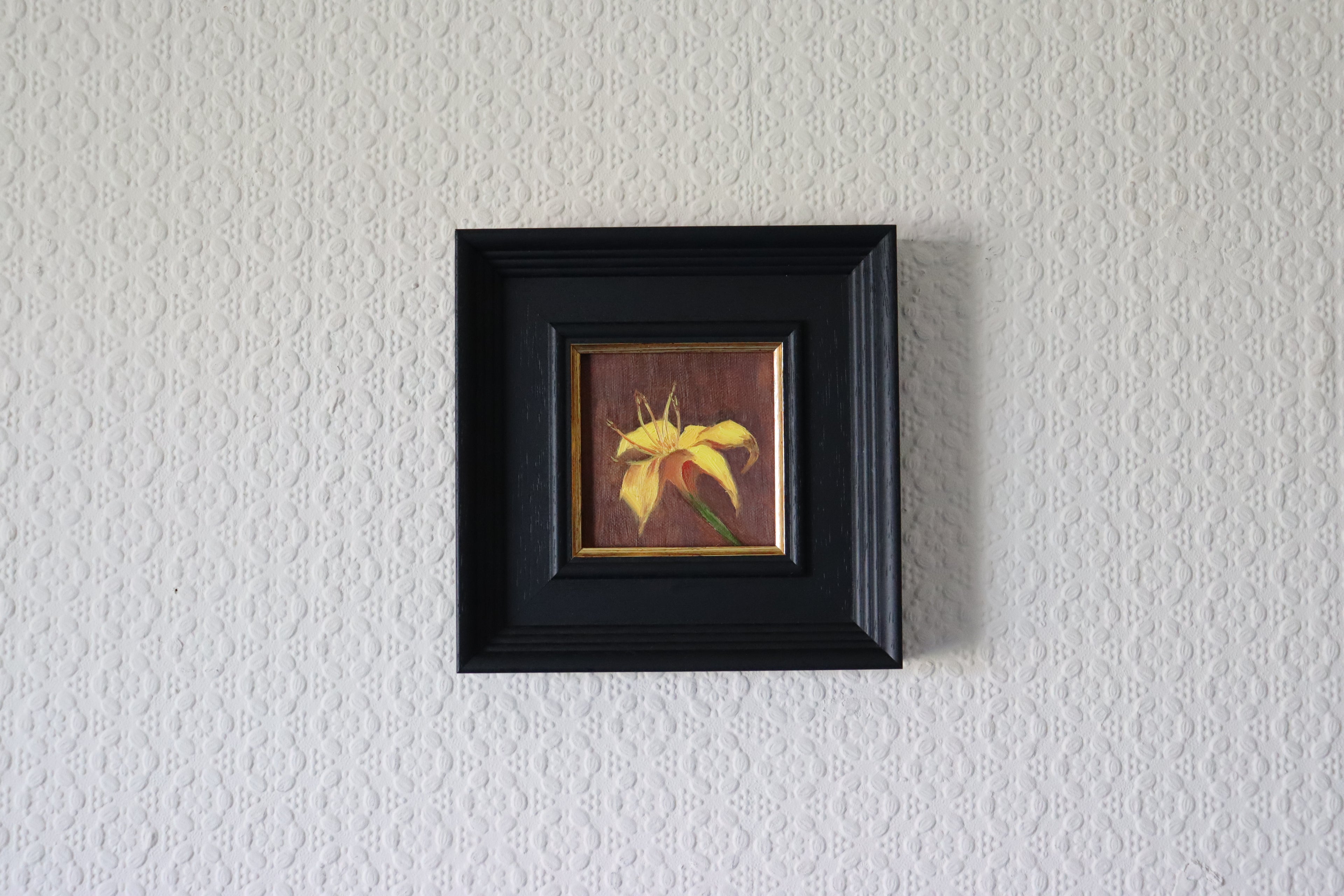 Small framed artwork of a yellow flower on a textured white wall Original oil painting of a yellow lily, vibrant floral still life by Marta Stolarska Fine Art