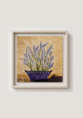 Framed wall art featuring a textured painting of lavender in a purple pot against a warm beige background, displayed on a light neutral wall.